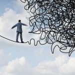 man on a thin line walking toward knotted rope