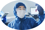 Confident healthcare scientist in blue biohazard suit and safety goggles standing in laboratory and working with dangerous sample