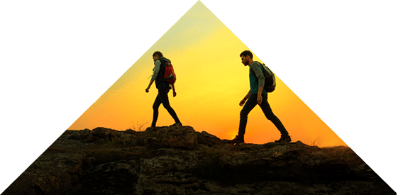 Couple of Young Happy Travelers Hiking with Backpacks on the Beautiful Rocky Trail at Warm Summer Sunset  Family Travel and Adventure Concept 